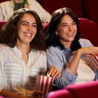 Laughing Young Women Enjoying Movie in Cinema