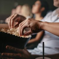 Young people eating popcorn in movie theater